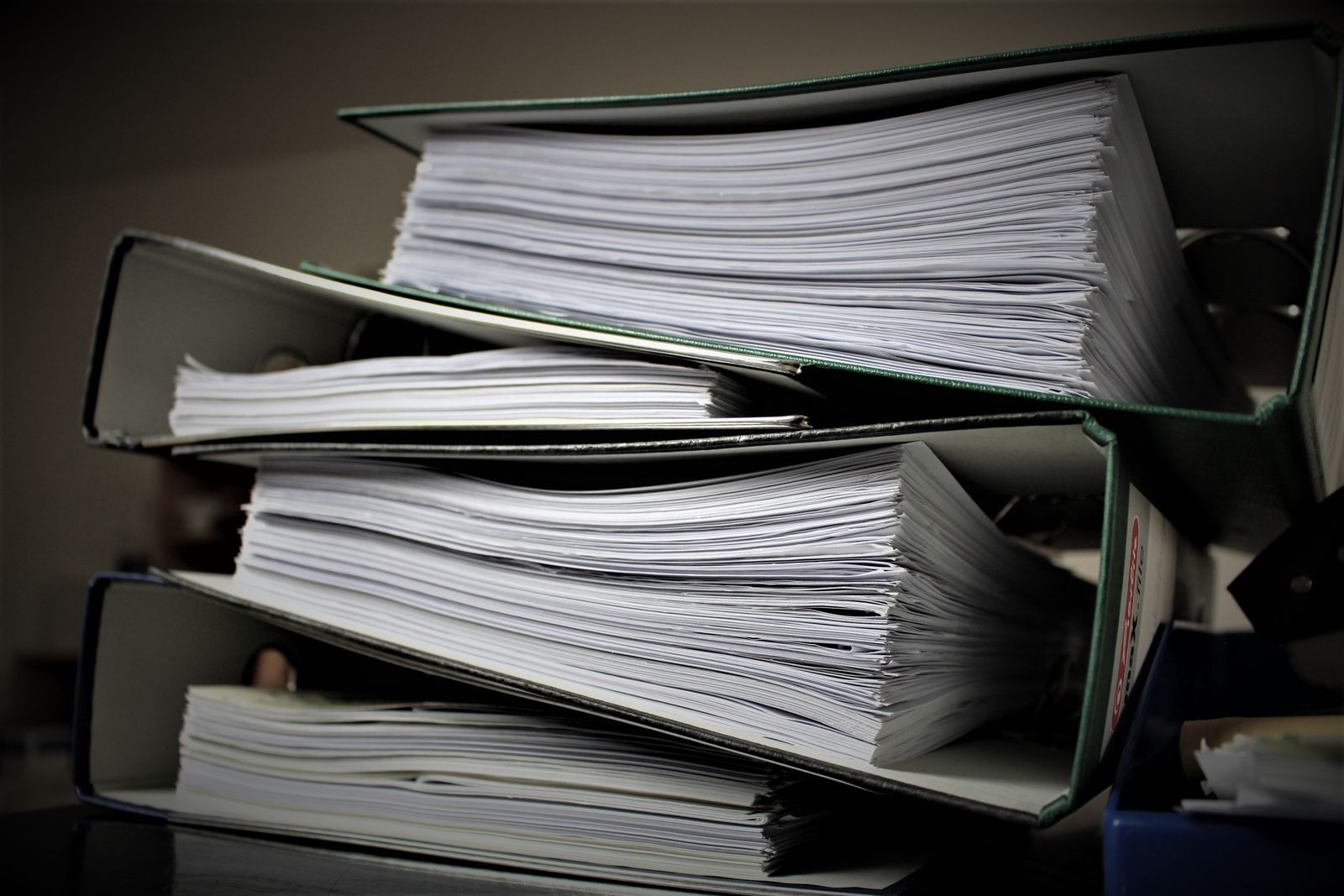 Varios archivadores de anillas apilados y llenos de documentos, en primer plano