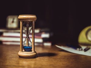 Reloj de arena sobre una mesa de madera, símbolo de la espera en los juzgados