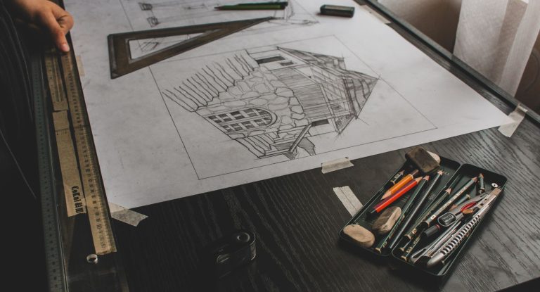 Boceto a lápiz de un edificio sobre una mesa de dibujo, con escuadra, regla y lápices