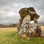 Dolmen de grandes piedras en un prado bajo un cielo nublado, imagen de archivo