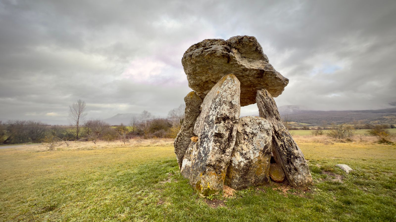 Dolmen de grandes piedras en un prado bajo un cielo nublado, imagen de archivo