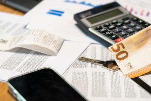Billete de 50 euros, calculadora y llave sobre documentos financieros