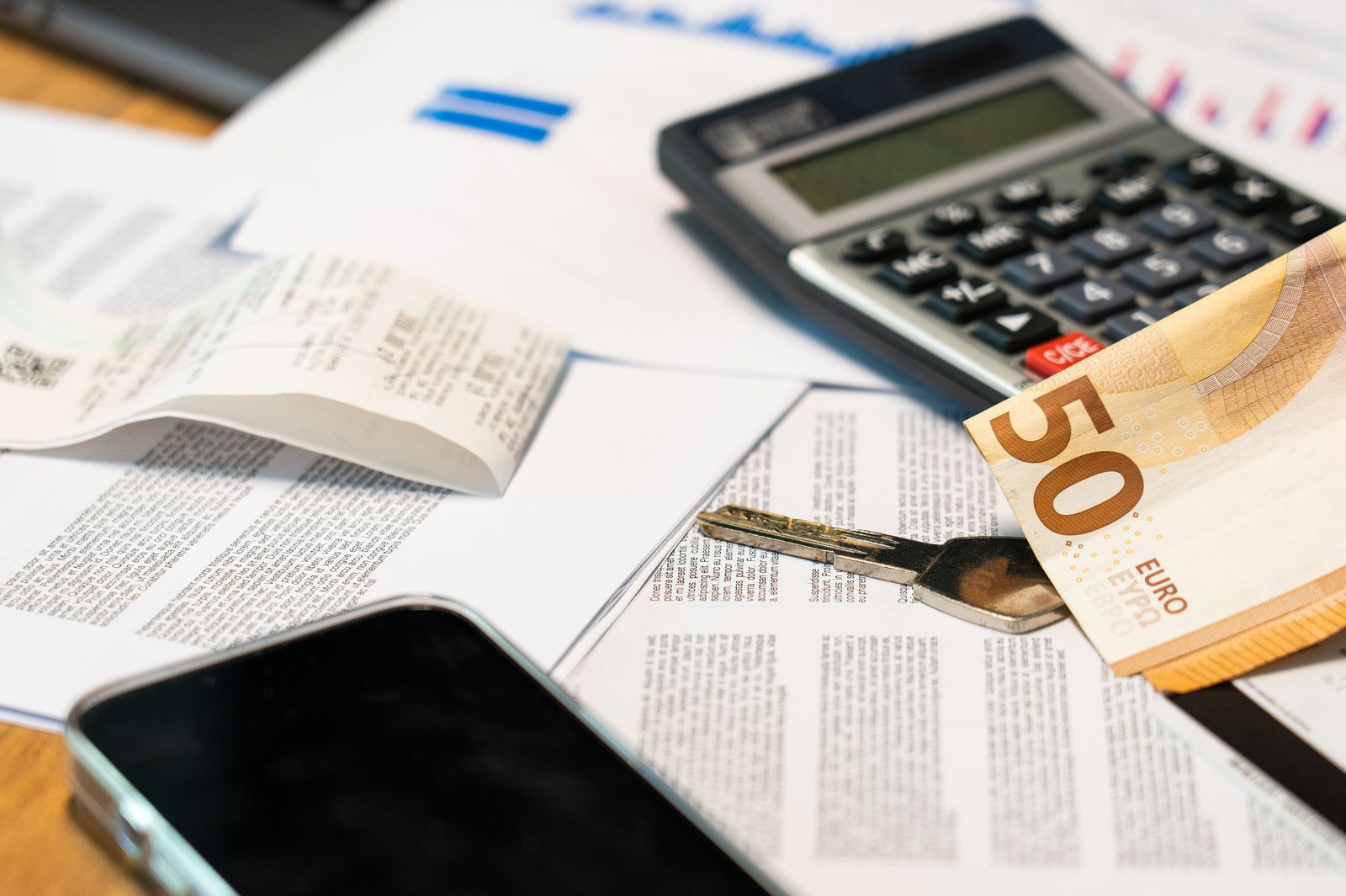 Billete de 50 euros, calculadora y llave sobre documentos financieros
