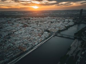 Vista aérea de Sevilla al atardecer, con el río Guadalquivir y los puentes en primer plano