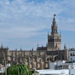 La Giralda y la Catedral de Sevilla vistas desde una azotea, con cielo azul y nubes