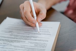 Primer plano de una mano que firma un documento con un bolígrafo blanco